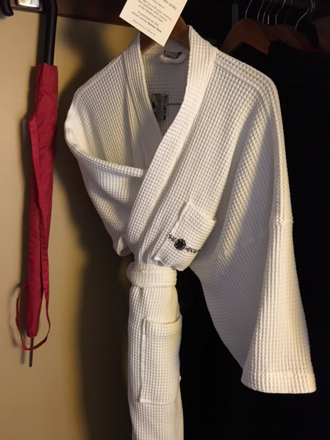 folded bath robe hanging from coat hanger in a closet