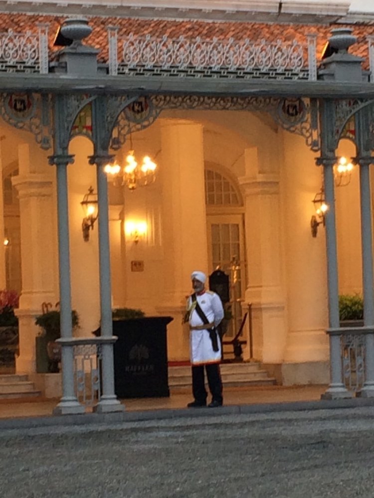 bellman standing in front of The Raffles Hotel in Singapore